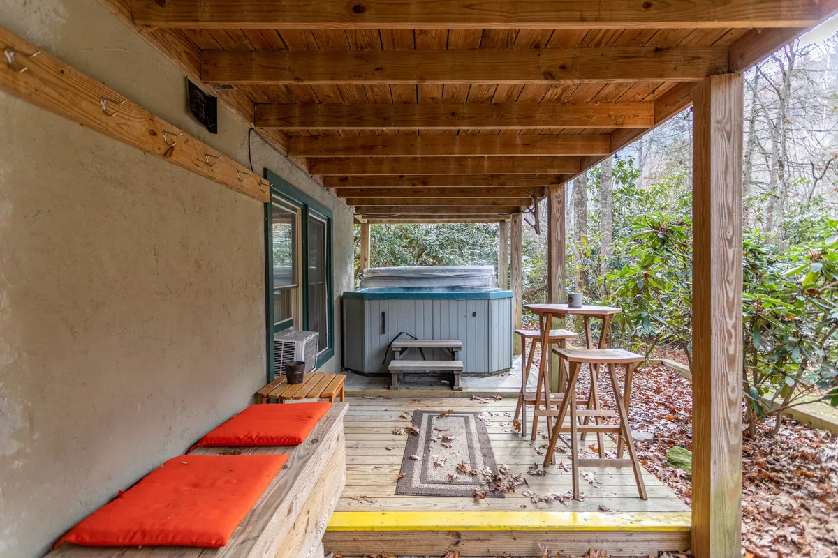 A tranquil outdoor deck featuring a bubbling hot tub surrounded by wooden seating and natural greenery. The space exudes relaxation and is perfect for unwinding after a day of play, with the hot tub as a focal point for year-round enjoyment.